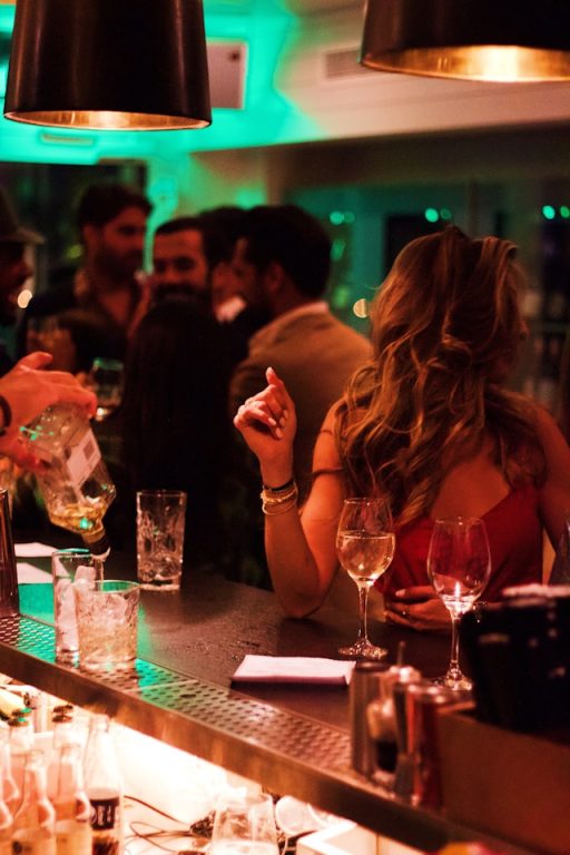 People at a bar talking. A woman in the foreground.